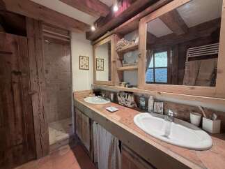 Experience rustic charm in this bathroom featuring a double vanity with terracotta tile countertops and a spacious walk-in shower.