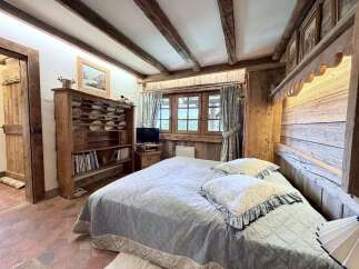 Experience rustic charm in this cozy bedroom featuring exposed wooden beams and a traditional plate rack hutch.