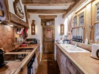 Experience rustic charm in this cozy kitchen, featuring exposed wooden beams and a unique hexagonal tile backsplash.