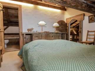 Experience rustic charm in this unique bedroom featuring exposed wooden beams and a cozy, traditional aesthetic.