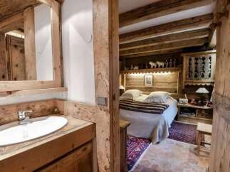 Experience rustic charm in this cozy bedroom featuring exposed wooden beams and a charming vanity area.
