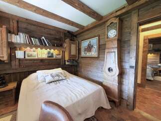 Experience rustic charm in this cozy bedroom featuring exposed wooden beams and walls, creating a warm and inviting atmosphere.