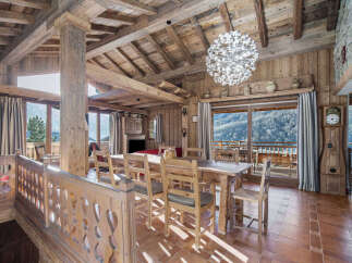 Experience luxurious mountain living in this stunning chalet, featuring a grand dining area with a rustic wooden table and chairs, perfect for family gatherings.