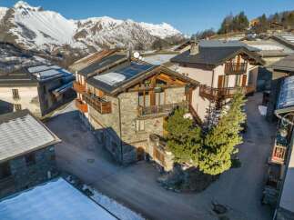 Experience alpine living in this charming stone and wood chalet, nestled amidst breathtaking snowy mountain vistas.