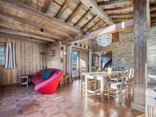 Experience rustic charm in this mountain retreat featuring a vibrant red sofa and a cozy dining area with a wooden table and chairs.