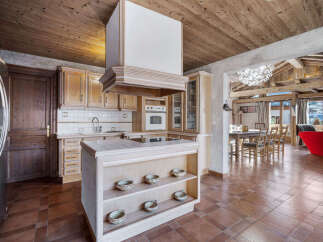 Experience rustic charm in this spacious kitchen featuring warm wooden cabinetry and a central island with a built-in stovetop.