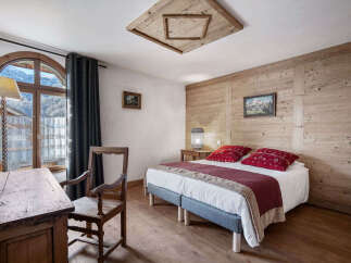 Experience rustic charm in this cozy bedroom featuring a comfortable bed adorned with vibrant red accent pillows and a warm, textured quilt.