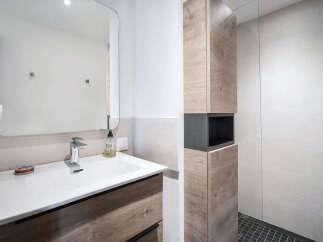 This modern bathroom features a sleek vanity with a white basin and chrome faucet, complemented by a large, rounded mirror.