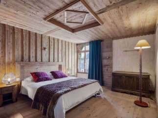 Experience rustic charm in this cozy bedroom, featuring warm wooden walls and a unique geometric ceiling design.
