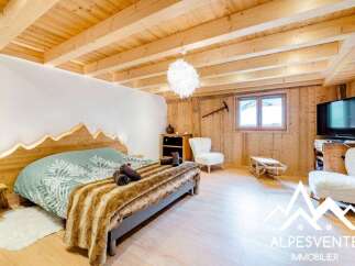 Experience cozy mountain living in this charming bedroom featuring a unique wooden headboard with integrated lighting, designed to resemble mountain peaks.