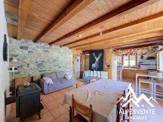 Experience rustic charm in this inviting living space featuring exposed wooden beams and a stone accent wall.