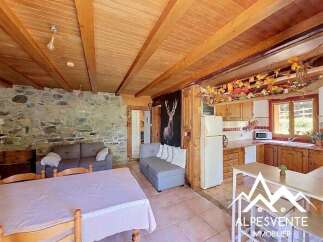 Experience rustic charm in this cozy living space featuring exposed wooden beams and a stone accent wall.