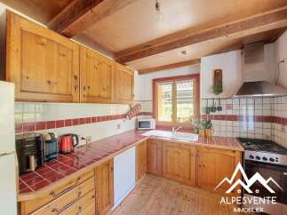 Discover this charming kitchen featuring rustic wooden cabinetry and warm red tiled countertops, perfect for a cozy home.