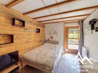 This charming bedroom features a cozy double bed with a nature-inspired duvet cover, set against a warm, wood-paneled wall.