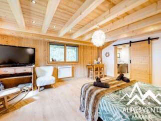 Experience cozy mountain living in this charming studio apartment, featuring a warm wooden interior and exposed beams.