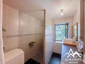 This charming bathroom features a spacious walk-in shower with stone accents and a decorative tile border.