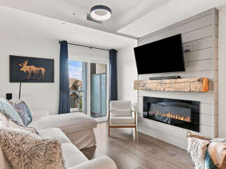Experience modern comfort in this inviting living room, featuring a sleek electric fireplace with a rustic wood mantel and a large flat-screen TV.