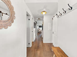 Step into this charming hallway featuring a decorative woven mirror and a rustic wooden bench, perfect for a welcoming entryway.