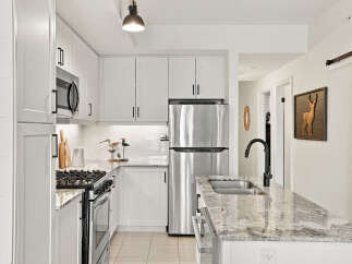 Discover this modern kitchen featuring sleek white cabinetry and granite countertops.