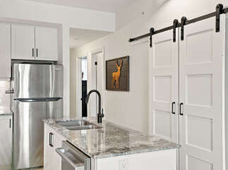 Discover modern living in this stunning kitchen featuring sleek white cabinetry and a gleaming stainless steel refrigerator.