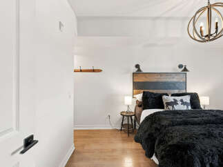 Experience rustic charm in this cozy bedroom, featuring a striking wood-slat headboard and plush black bedding.