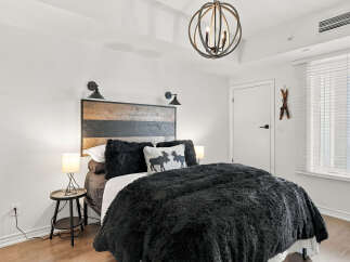 Experience rustic charm in this inviting bedroom, featuring a striking wood-plank headboard and plush black bedding for ultimate comfort.