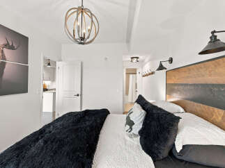 Experience rustic charm in this master bedroom, featuring a striking wood-paneled headboard and a plush black faux fur throw.
