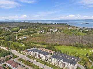 Experience modern living in this stunning aerial view showcasing a vibrant community adjacent to a serene lake and lush green golf course.