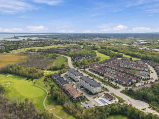 Experience luxury living in this stunning aerial view showcasing modern townhomes and apartment buildings adjacent to a pristine golf course.