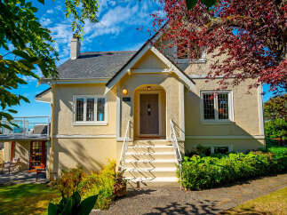 Charming home featuring a welcoming facade with a covered entryway and a bright yellow exterior.