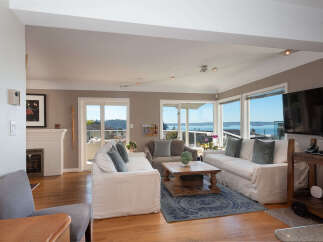 Experience breathtaking water views from this stunning living room, featuring a cozy fireplace and ample natural light.