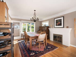 This charming dining room features a rustic wooden dining table set for four, illuminated by an elegant chandelier.