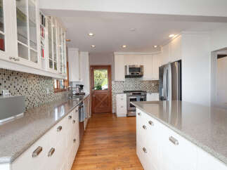 Experience culinary excellence in this beautifully appointed kitchen, featuring sleek white cabinetry, sparkling granite countertops, and a stylish mosaic tile backsplash.