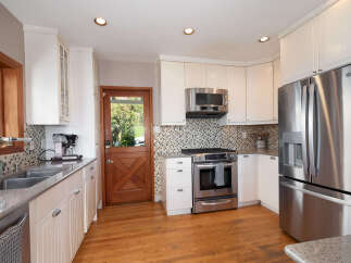Step into this charming kitchen featuring pristine white cabinetry and a stylish mosaic tile backsplash.