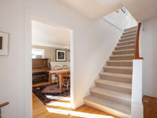 Step into this charming home featuring a welcoming entryway with a grand staircase and a glimpse into a cozy dining area.