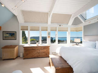 Experience breathtaking water views from this stunning bedroom, featuring a wall of windows that flood the space with natural light.