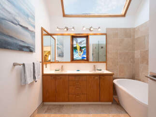 Experience luxury in this stunning bathroom featuring a freestanding bathtub and a spacious double vanity with ample storage.