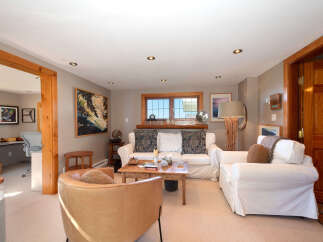 Step into this inviting living room, featuring a cozy seating area with plush white sofas and a warm leather armchair.