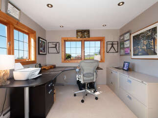 This home office features a spacious L-shaped desk with a printer and a comfortable ergonomic chair, perfect for productivity.
