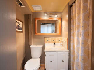This charming bathroom features a white toilet and a vanity with a white countertop and a chrome faucet.