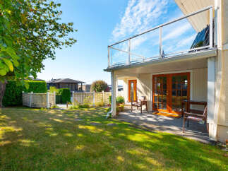 Enjoy outdoor living in this charming backyard featuring a lush green lawn and a white lattice fence.