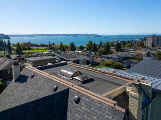 Experience breathtaking panoramic views from this stunning property, featuring a modern flat roof with unique skylights and a sleek, curved metal roofline.