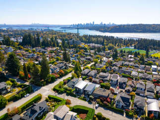 Discover this stunning aerial view of a vibrant neighborhood showcasing a mix of modern and traditional homes nestled amongst lush greenery and colorful autumn foliage.
