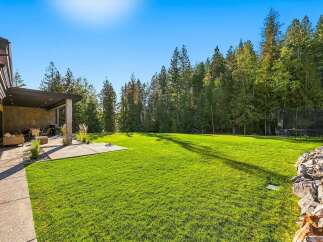 Experience luxurious outdoor living with this expansive backyard, featuring a covered patio perfect for entertaining and a vast, manicured lawn ideal for recreation.