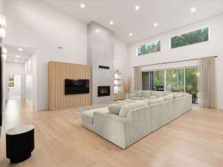 Experience modern luxury in this spacious living room featuring a soaring fireplace and a sleek entertainment center.