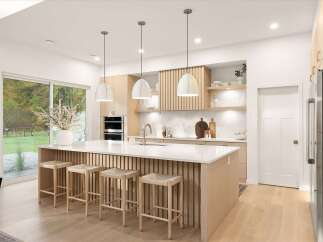 Experience modern luxury in this stunning kitchen, featuring a spacious island with a waterfall countertop and sleek vertical wood paneling.