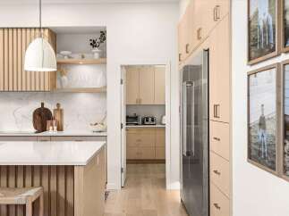 Experience modern living in this stunning kitchen featuring sleek, light wood cabinetry and a spacious island with a waterfall countertop.