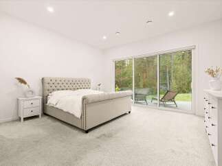 Experience luxury living in this spacious master bedroom featuring a stunning tufted sleigh bed and elegant nightstand.