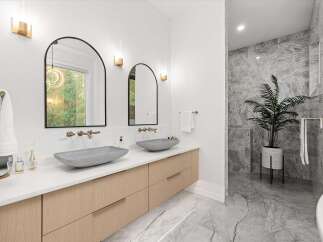 Experience modern luxury in this stunning bathroom featuring dual vessel sinks atop a sleek, floating wood vanity.