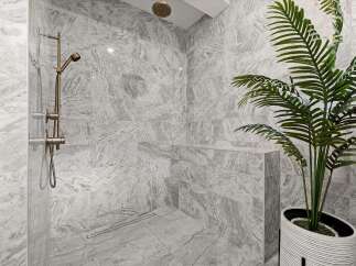 Experience modern luxury in this stunning bathroom featuring a spacious walk-in shower with elegant marble-look tiles.